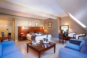 安道尔城Fènix Hotel的酒店客房配有床、沙发和桌子。