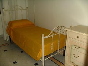 韦列Villa Gloria Bed & Breakfast的梳妆台旁一张带黄色毯子的小床