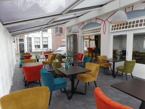 弗利辛恩弗利辛恩别墅酒店的餐厅设有桌子和五颜六色的椅子