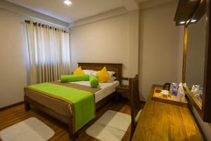 努沃勒埃利耶希尔普赖德城市酒店的一间卧室配有一张带绿色枕头的床