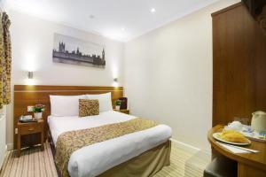 伦敦皇后公园酒店的配有一张床和一张书桌的酒店客房