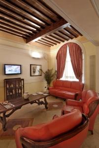 比萨波罗格纳酒店的客厅配有红色皮革家具和桌子