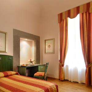 比萨波罗格纳酒店的一间卧室设有两张床、一张桌子和一个窗口。