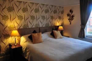 格洛斯特爱德华酒店的一间卧室配有一张大床和两盏灯