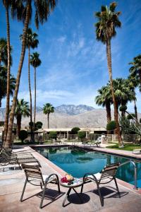 棕榈泉Desert Isle Resort, a VRI resort的一个带两把椅子的游泳池,棕榈树