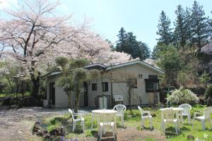 富士河口湖西宫荘酒店的一组白色的桌椅,位于房子前面
