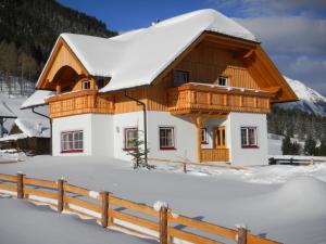 WeisspriachFerienhaus Longa的雪覆盖的房屋,有栅栏