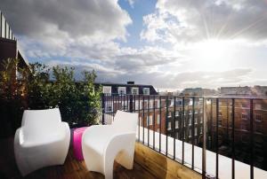伦敦阿佩克斯顶点寺苑酒店的阳台配有两把白色椅子和太阳