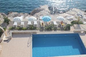普利莫顿Villa Simpatia的毗邻大海的带椅子和遮阳伞的游泳池