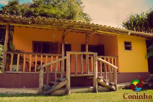InhaúmaHotel Fazenda Coninho的黄色房子前面设有木门廊