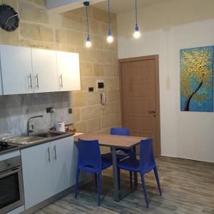 森格莱阿Senglea Apartments的厨房配有木桌和蓝色椅子
