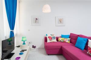 德尔锡伦西奥海岸大力士公寓的客厅配有粉红色的沙发和电视