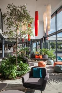 勒梅尼尔阿姆洛巴黎戴高乐机场游牧酒店的大堂配有沙发,种植了树木和植物