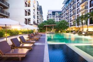 曼谷于拉查达阿曼塔酒店的酒店游泳池设有躺椅和遮阳伞