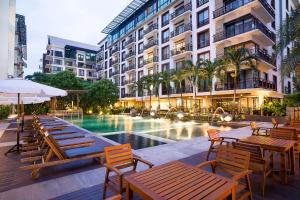 曼谷于拉查达阿曼塔酒店的酒店庭院设有桌椅和游泳池
