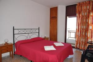 拉雷斯廷加雷斯廷加公寓的一间卧室配有红色的床和2条毛巾
