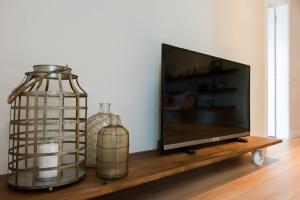 巴塞罗那宝拉木西卡公寓的两瓶玻璃瓶旁的平面电视