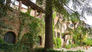 卢奇尼亚诺Residenza d'Epoca Il Cassero的前面有一棵树的大型砖砌建筑