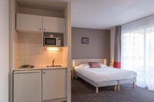 拉罗谢尔Appart'City Classic La Rochelle Centre的一间带床的小卧室和一间厨房
