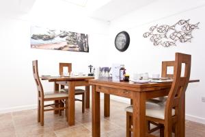 基督城Avon Beach Bed & Breakfast的一间设有两张桌子和墙上一个时钟的餐厅