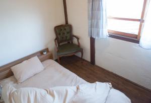 长野长野多特旅舍的卧室配有床、椅子和窗户。