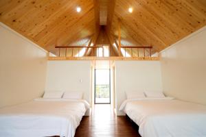 头城工匠家阁楼小木屋的配有木天花板的客房设有两张床。