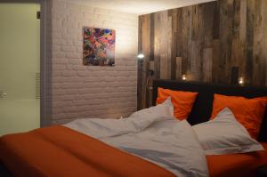 穆斯克龙Les Chambres d'Elza的一张带橙色和白色枕头的床和绘画