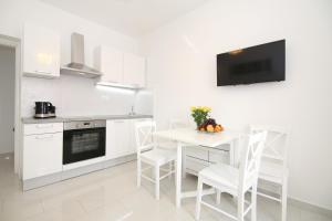 斯普利特Apartment LU的白色的厨房配有白色的桌子和椅子