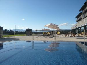 拉莫利纳HG拉莫利纳酒店的一座带椅子和遮阳伞的游泳池位于一座建筑旁边