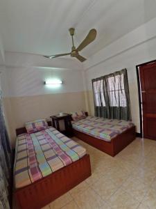 清迈莎拉旅馆的一间卧室配有两张床和吊扇