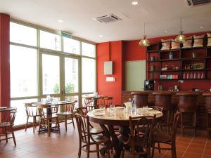 马六甲卡皮坦会馆精品酒店的一间设有桌椅的餐厅,位于带红色墙壁的房间