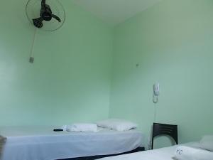 北茹阿泽鲁Pousada Cariri的白色的客房设有两张床和墙上的时钟