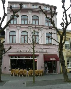 法尔肯堡杜普伊斯酒店的前面有黄色椅子的粉红色建筑