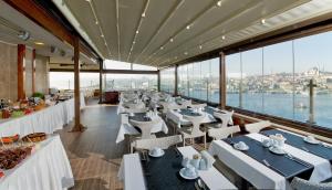 伊斯坦布尔伊斯坦布尔金城大酒店的餐厅设有白色的桌椅和窗户。