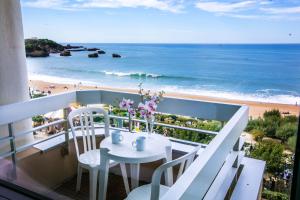 比亚里茨维多利亚冲浪酒店的一个带桌椅和海滩的阳台