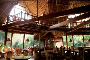 马尔多纳多港茵卡特拉雷瑟瓦亚马逊酒店的餐厅设有木桌、椅子和窗户。