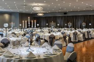 北安普敦Mercure Northampton的大型宴会厅配有白色的桌椅