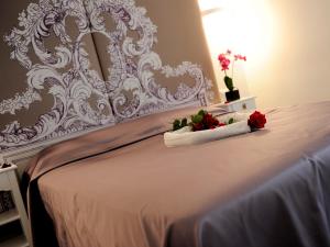 罗马简单客房旅馆的一张白色的床,上面有两朵红玫瑰