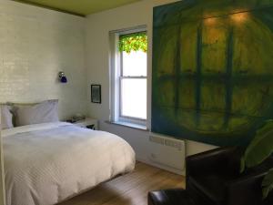 魁北克市乐253号住宿加早餐旅馆的一间卧室配有一张床,窗户配有绘画作品