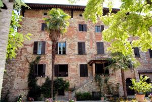 卢奇尼亚诺Residenza d'Epoca Il Cassero的一座古老的砖砌建筑,前面有棕榈树