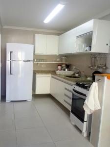 乌巴图巴Apartamento Avenida Wilson的厨房配有白色橱柜和白色冰箱。