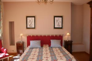 多尔多尼河畔博利厄格勒泽城堡酒店的一间卧室配有一张带红色床头板的床和两盏灯。