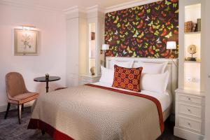 巴黎蒙赫酒店的卧室配有一张大床,墙上挂有绘画作品