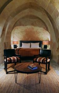 于尔居普索塔卡帕多西亚旅馆的一间卧室配有一张床、两把椅子和一张桌子