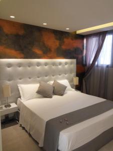 特罗佩阿米娜旅馆的卧室配有一张白色大床,墙上挂有绘画作品