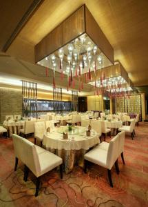 龙岗深圳雅邦朗悦国际酒店的餐厅配有白色的桌椅和吊灯