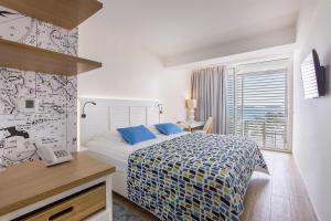 希贝尼克Amadria Park Beach Hotel Jure的一间卧室配有一张床、一张书桌和一个窗户。