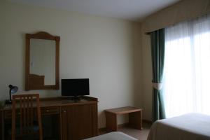 波多黎多德萨贡托奥地利76号酒店的一间卧室配有一张桌子、一台电视和一面镜子