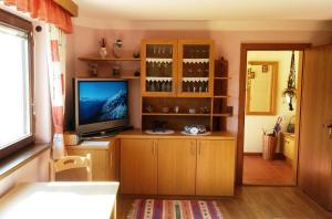 伊姆斯特Haus Reinstadler的客厅配有电视和带酒杯的橱柜