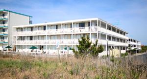 大洋城Seabonay Oceanfront Motel的海滩上的白色建筑,配有椅子和遮阳伞